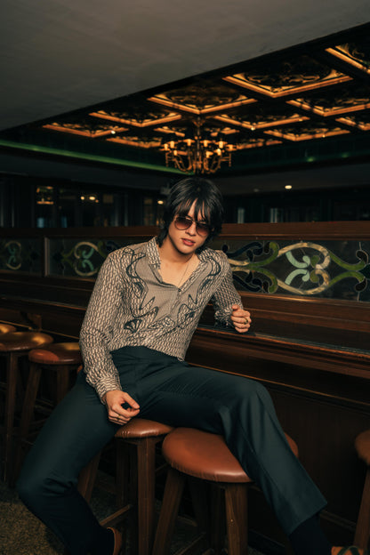 Man sitting on a bar stool in a dimly lit bar with a chandelier.
