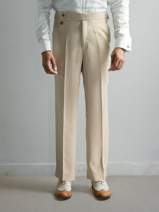 Beige dress pants worn with a white shirt and shoes on a plain background
