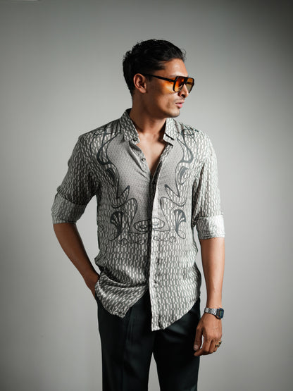 Man wearing a patterned shirt and sunglasses against a gray background