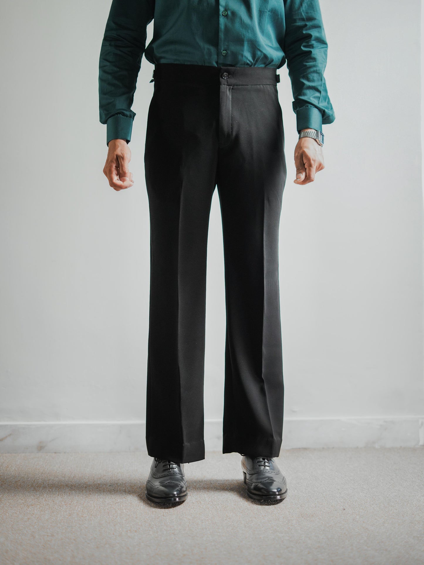 Person wearing a teal shirt and black pants against a plain background