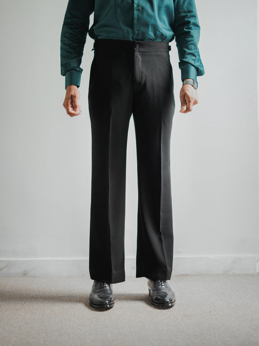 Person wearing a teal shirt and black pants against a plain background