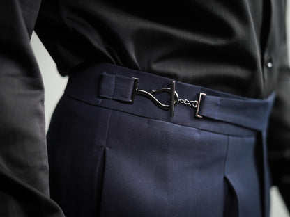 Navy blue pants with a belt featuring a silver buckle on a neutral background